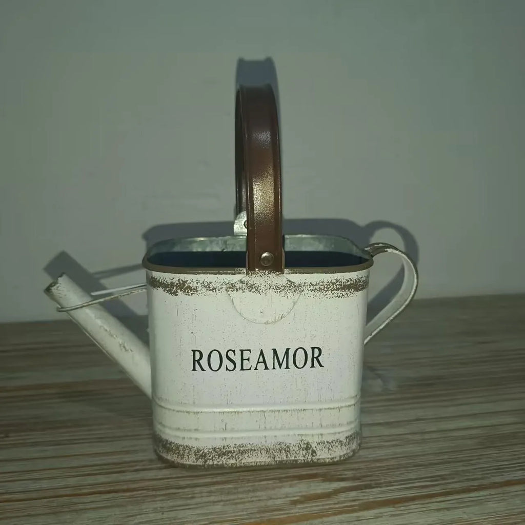 White metal watering can planter with brown handle, ROSEAMOR text on front