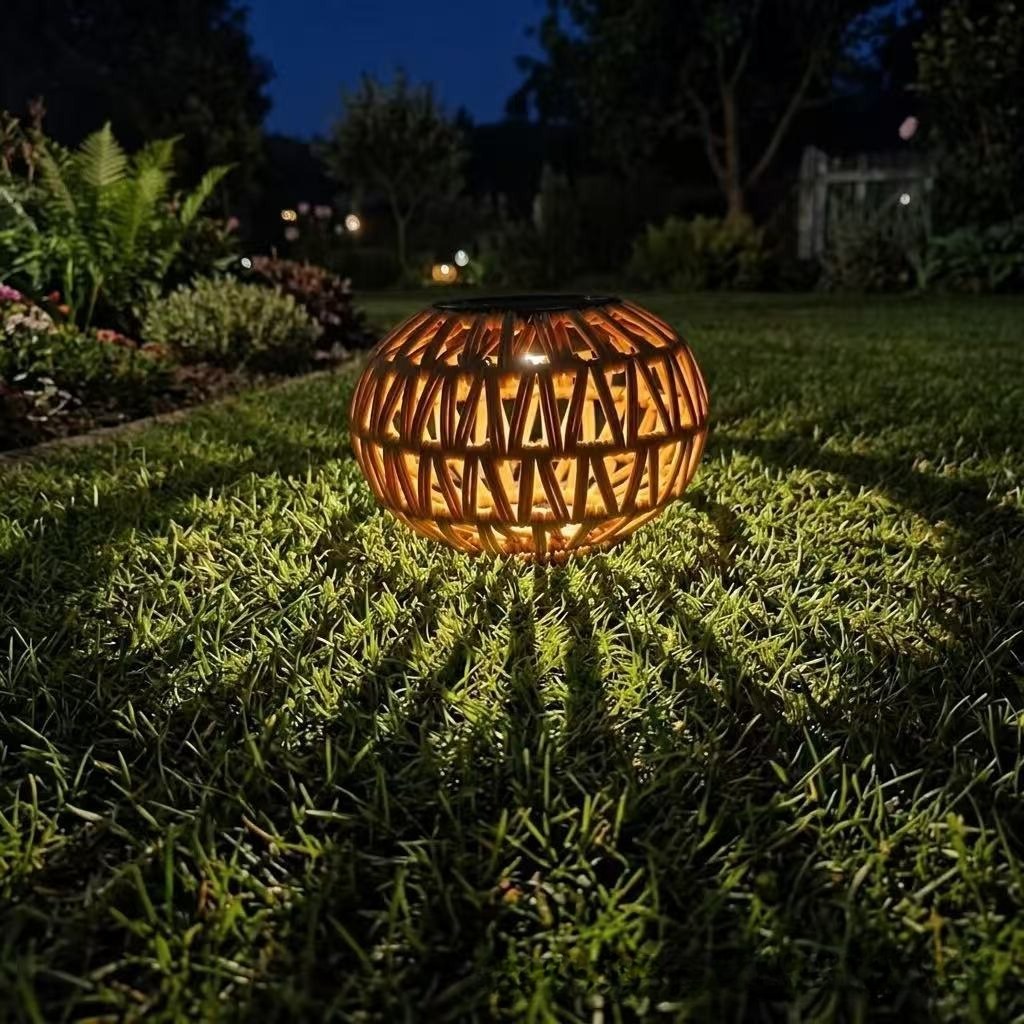 Woven rattan globe lantern with chain, warm light glowing outdoors at night