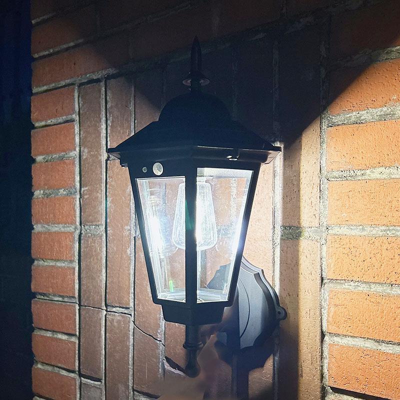 Black solar wall lantern with clear glass panels on a wall mount