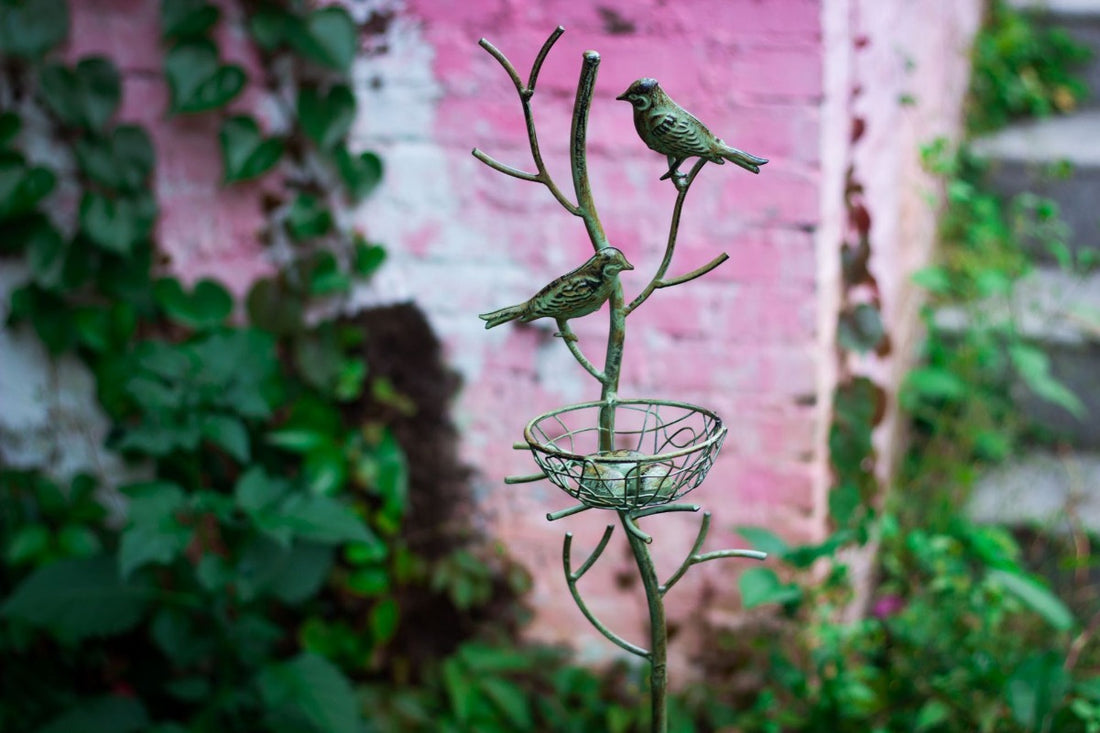 Dark green metal bird trellis stake with two birds perched above a wire nest basket