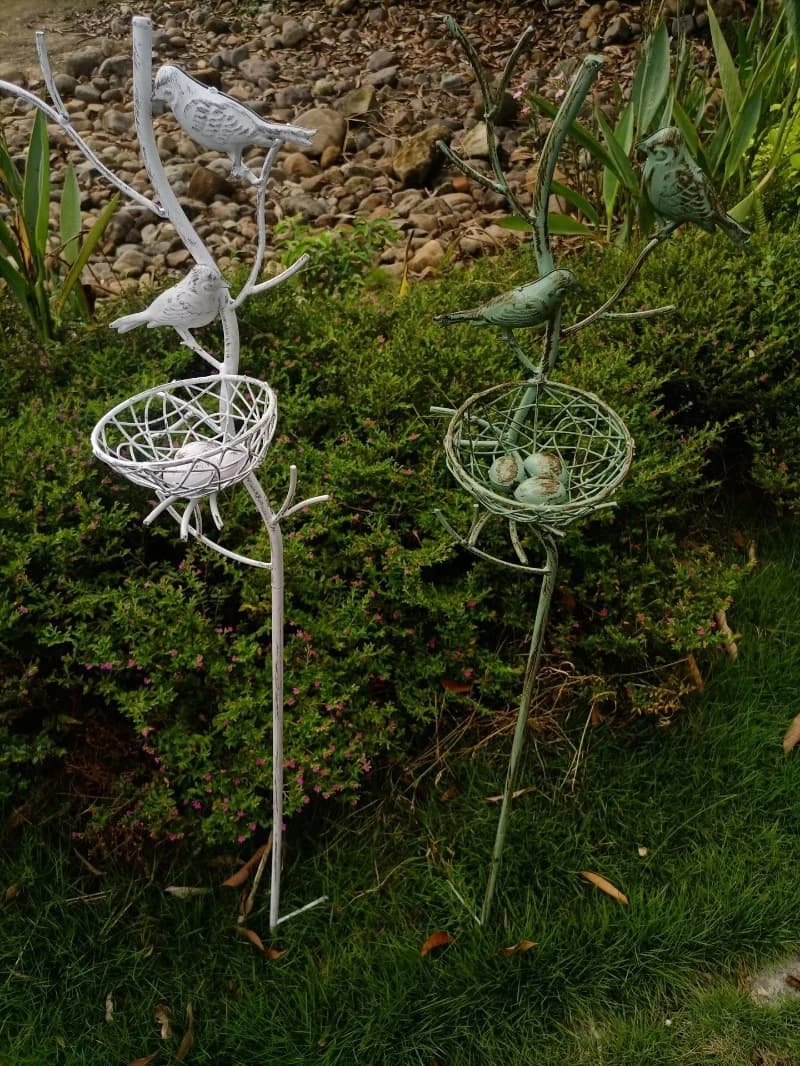 White and gray metal garden stake trellis with bird wire nest basket and two birds