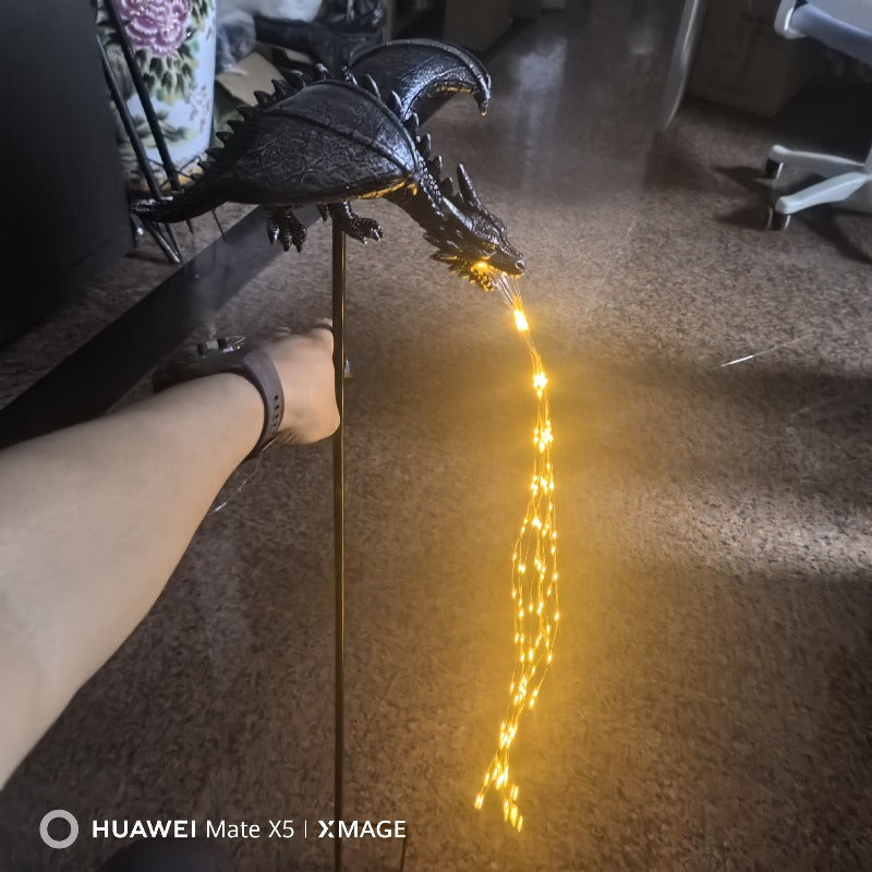 Lámpara de jardín con forma de dragón negro que brilla con luces cálidas en el suelo interior.