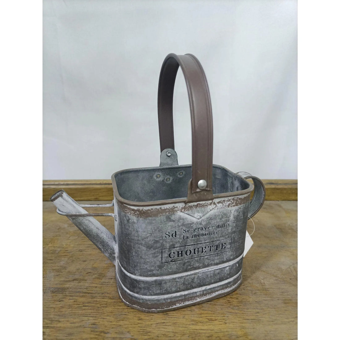 Gray metal watering can planter with brown handle, CHOUETTE label on front