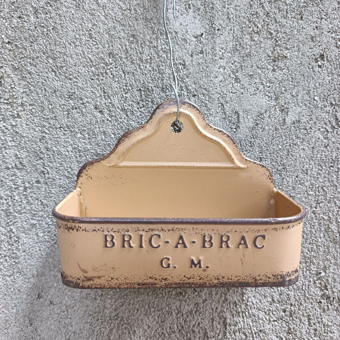 Beige hanging metal wall planter with “BRIC-A-BRAC G.M.” text.