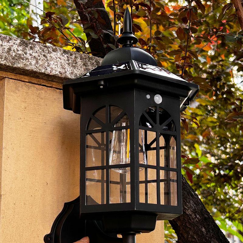 Solar wall sconce lantern with clear glass and black metal grid, wall-mounted