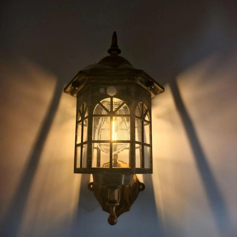 Bronze outdoor solar wall sconce lantern with warm light through glass window