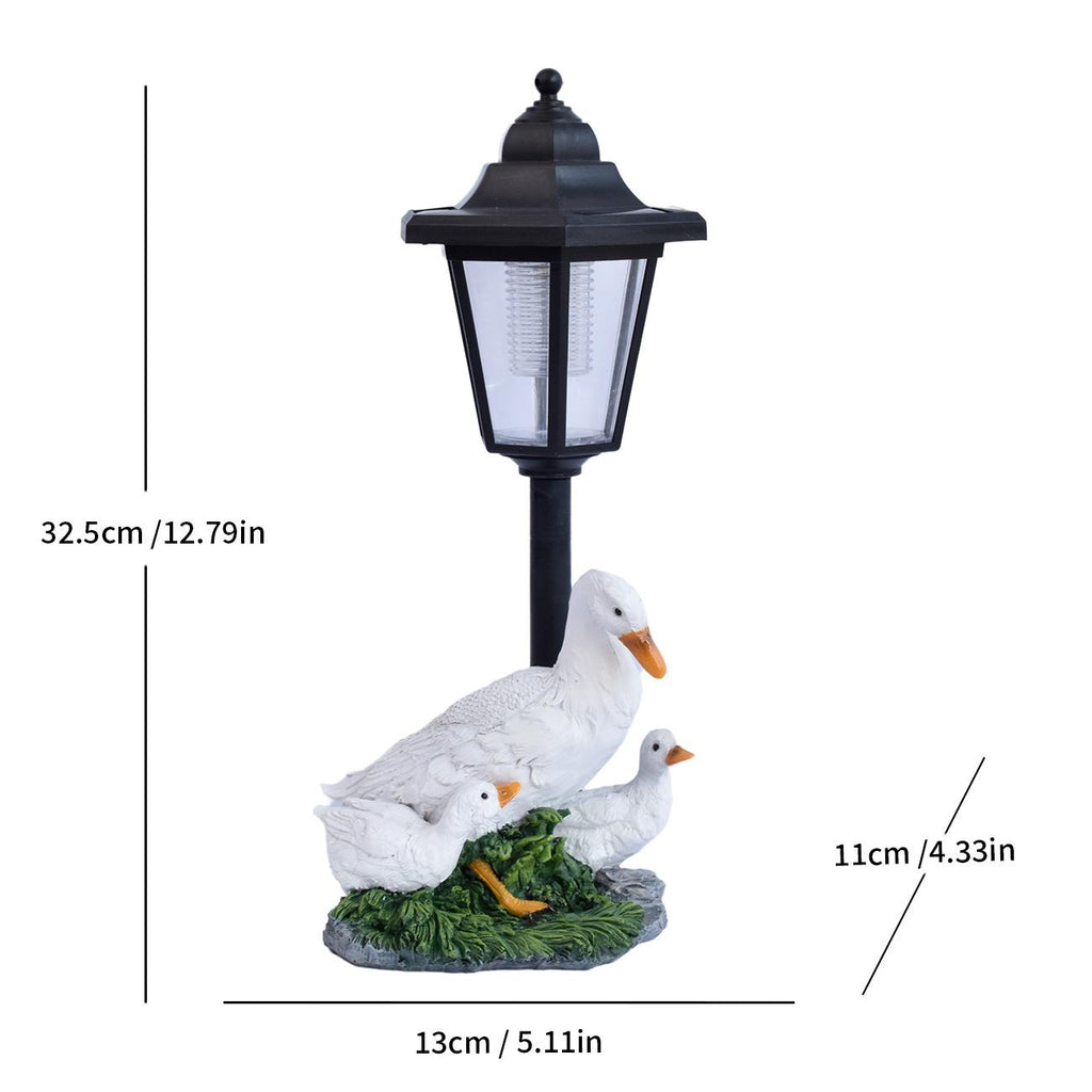 Solar LED lantern garden statue with white geese standing around a nest on grass