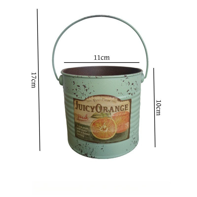 Grøn metalplantespand med buet håndtag og Juicy Orange-etiket, spættet finish