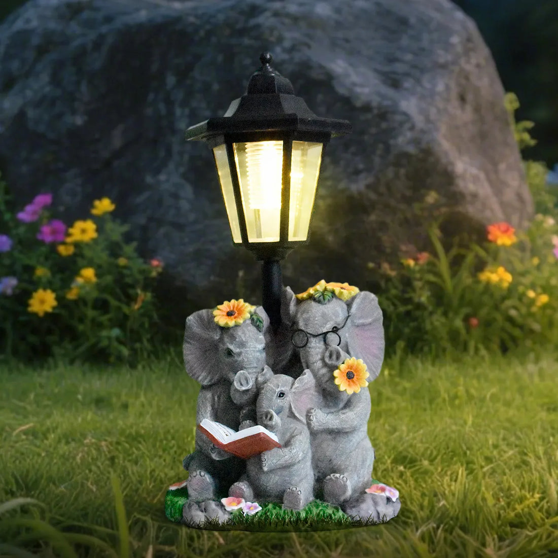 Hand-painted resin elephant family garden statue with glowing black LED lantern above flowers.