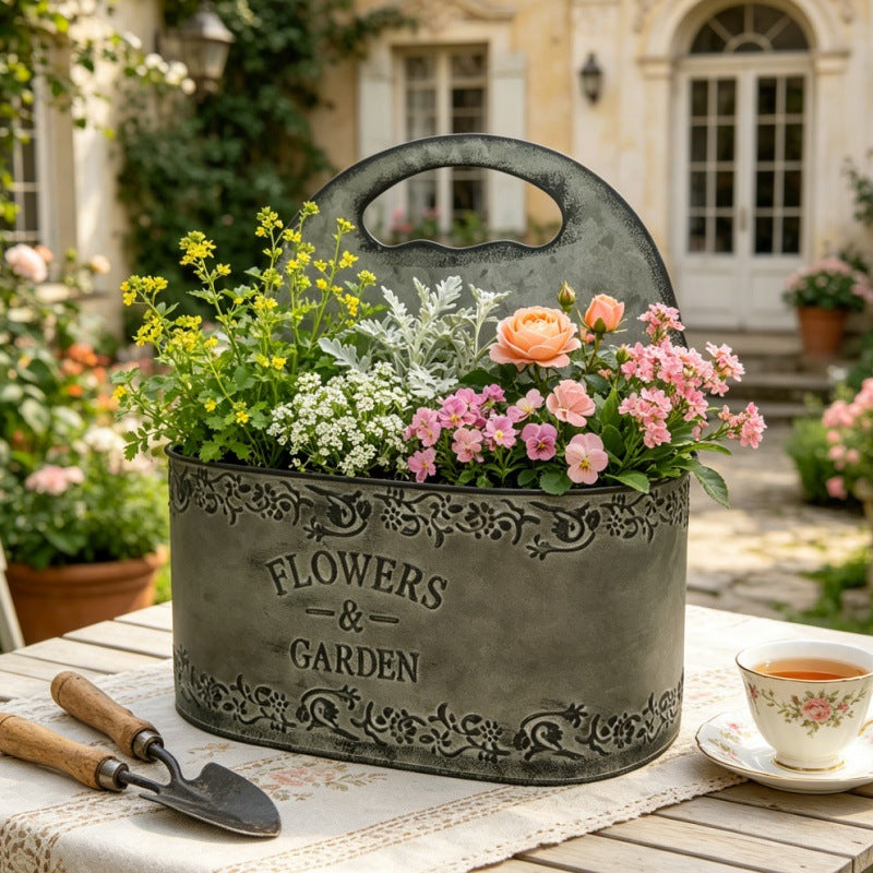 Antik blikmetalplantekasse med sidehåndtag og præget tekst "Blomster og have".