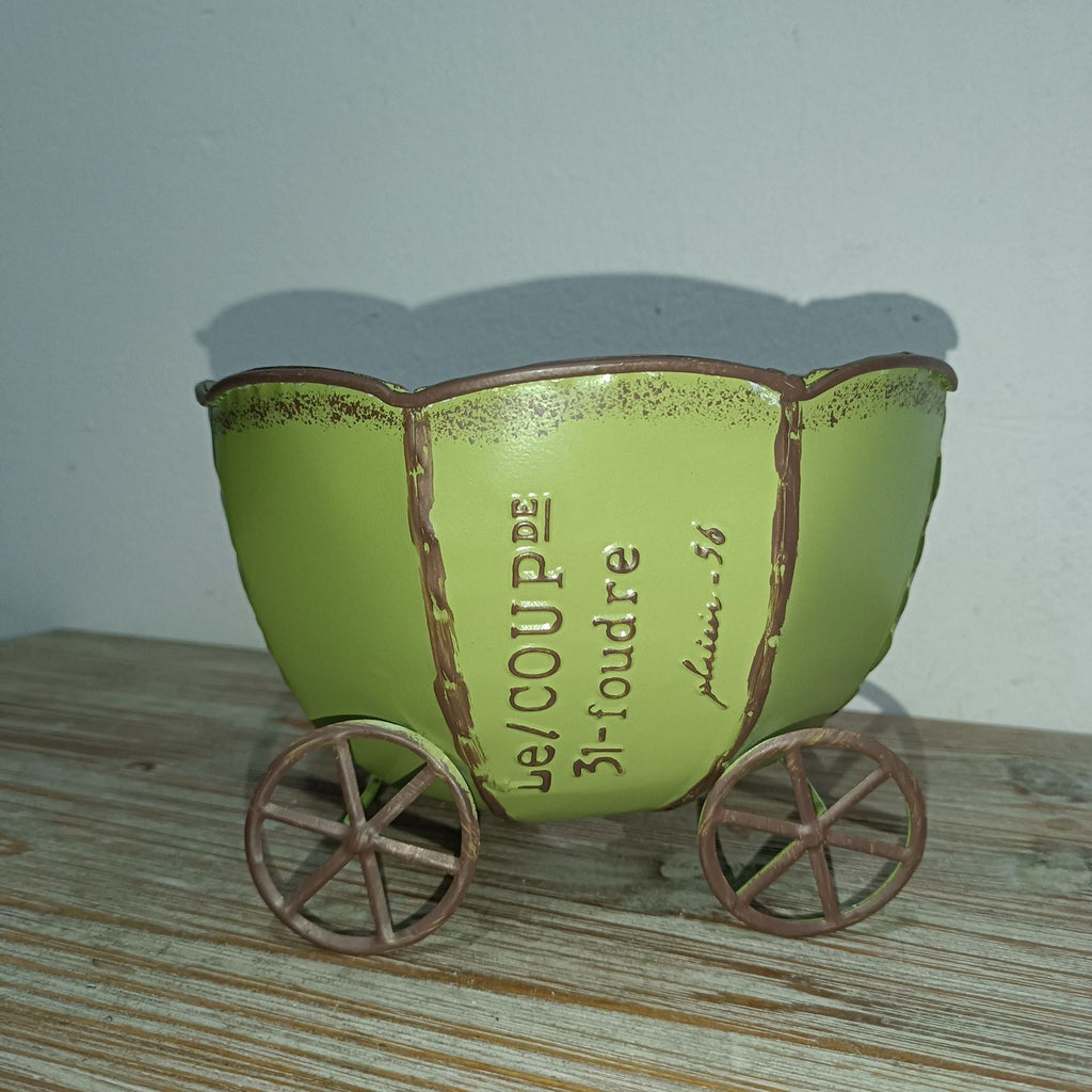 Green metal cart planter with engraved lettering and four decorative wheels