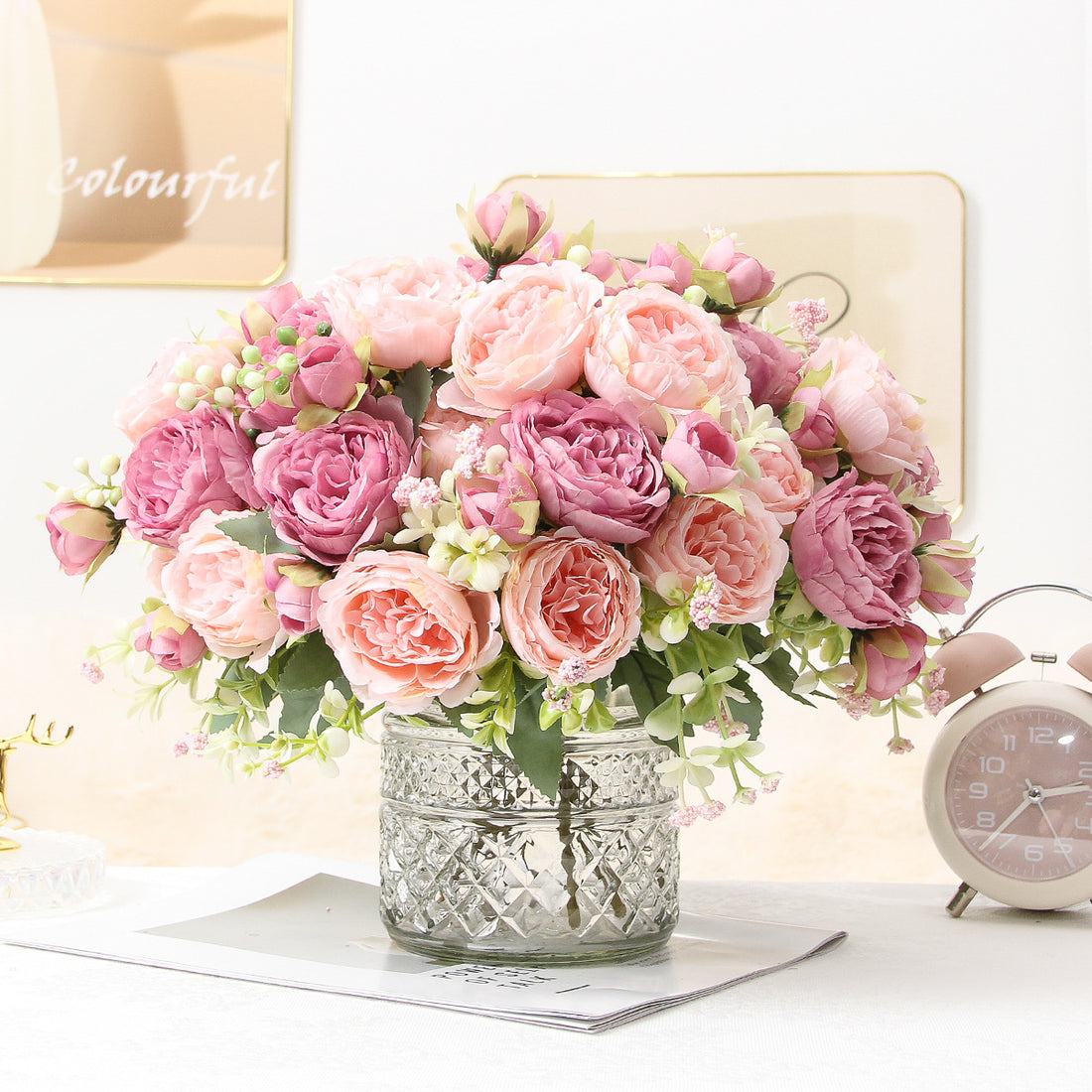 Pink faux peony bouquet in a textured silver vase, with small green filler blooms.