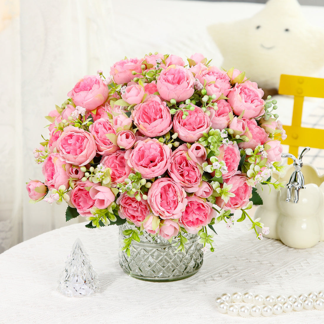 Pink faux peony bouquet with round blooms and green berry-like filler in a silver vase.