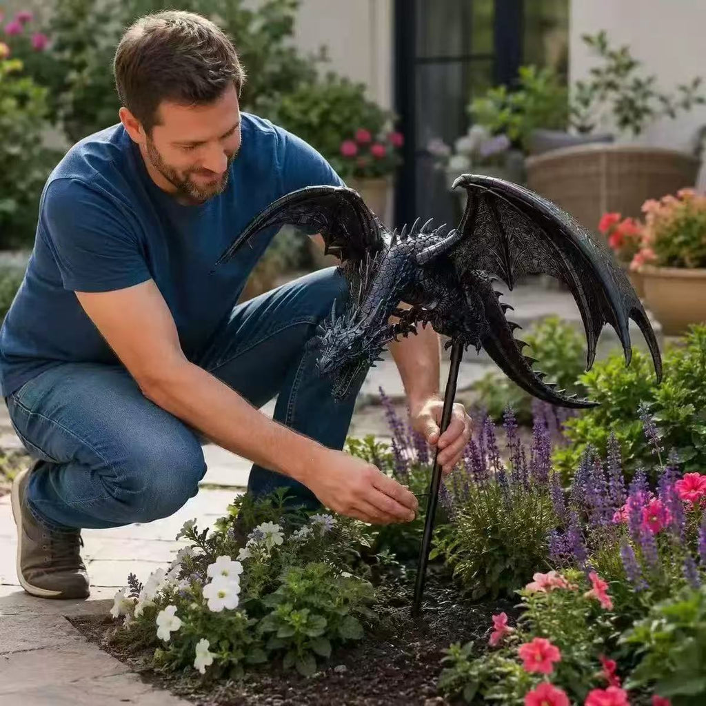 Lámpara de jardín con forma de dragón negro y guirnalda de luces cálidas colocada entre flores.