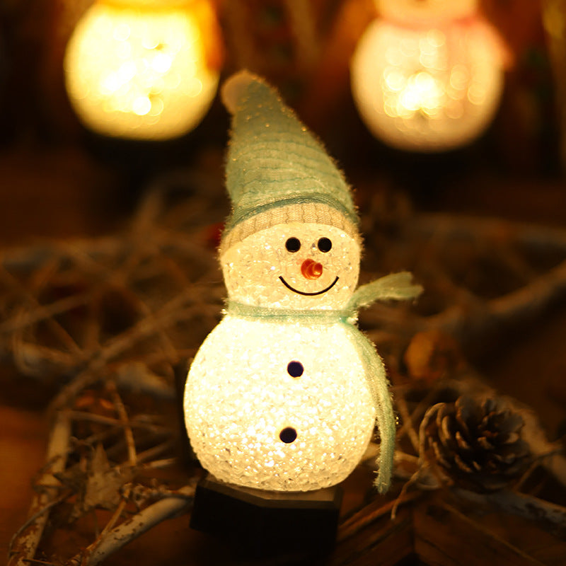 Solar snowman stake light with lit snowman, green hat and dark scarf