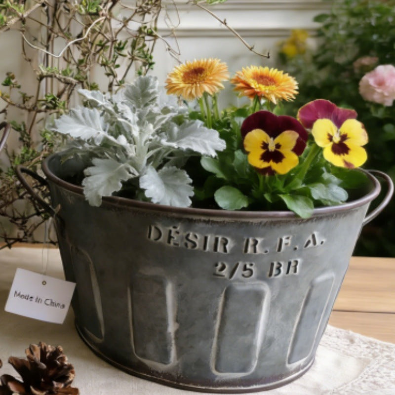 Galvaniseret metalplantespand med håndtag, fyldt med blomster