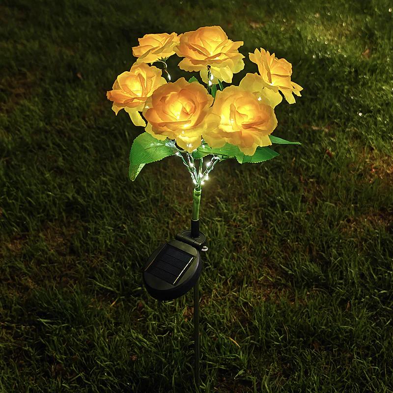 Solar rose garden stake light with yellow fabric roses, green leaves, and glowing solar base
