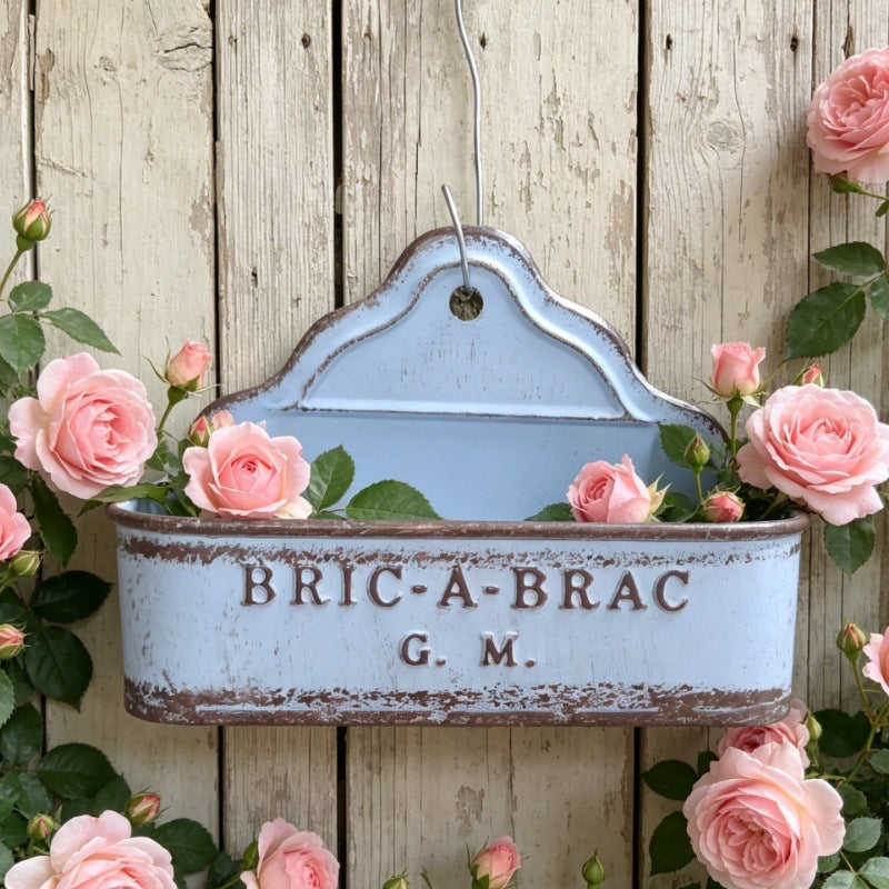Blue metal wall planter with “BRIC-A-BRAC G.M.” text and hanging loop.