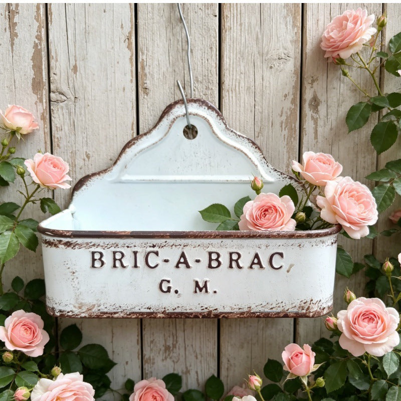 White distressed metal wall planter with hanging hook and rose flowers around