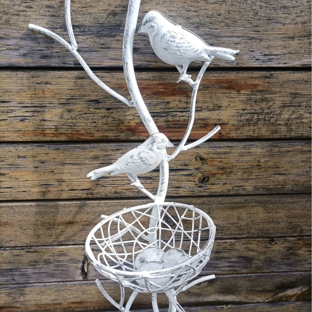 White metal bird nest garden stake detail with two perched birds above round wire nest