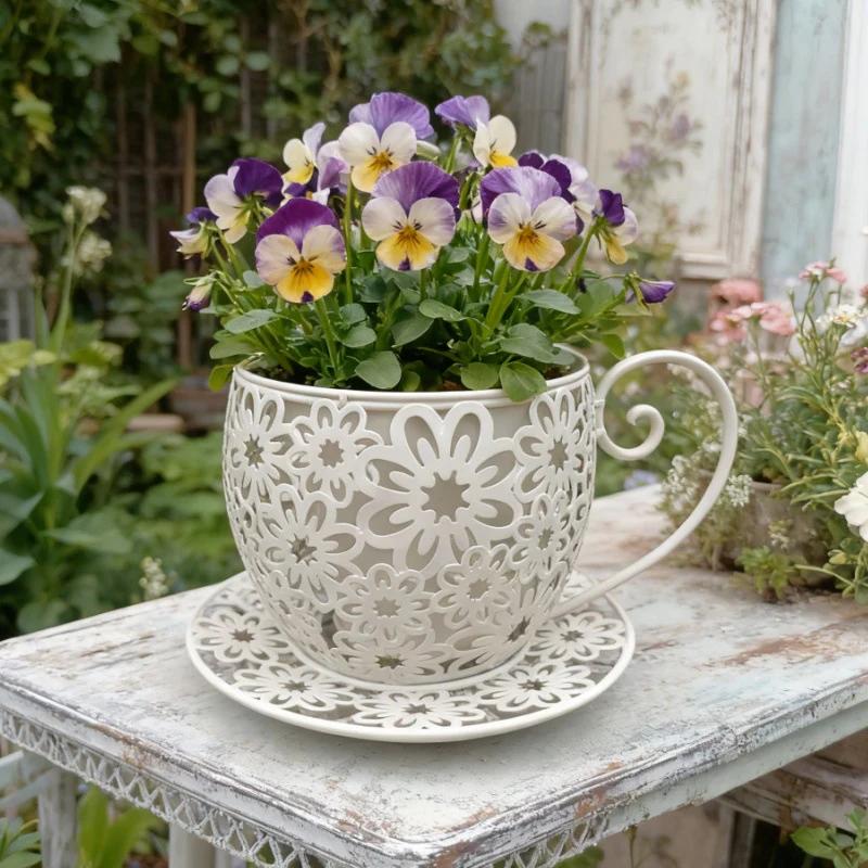 Decorative white teacup planter with purple and yellow flowers on a rustic table.