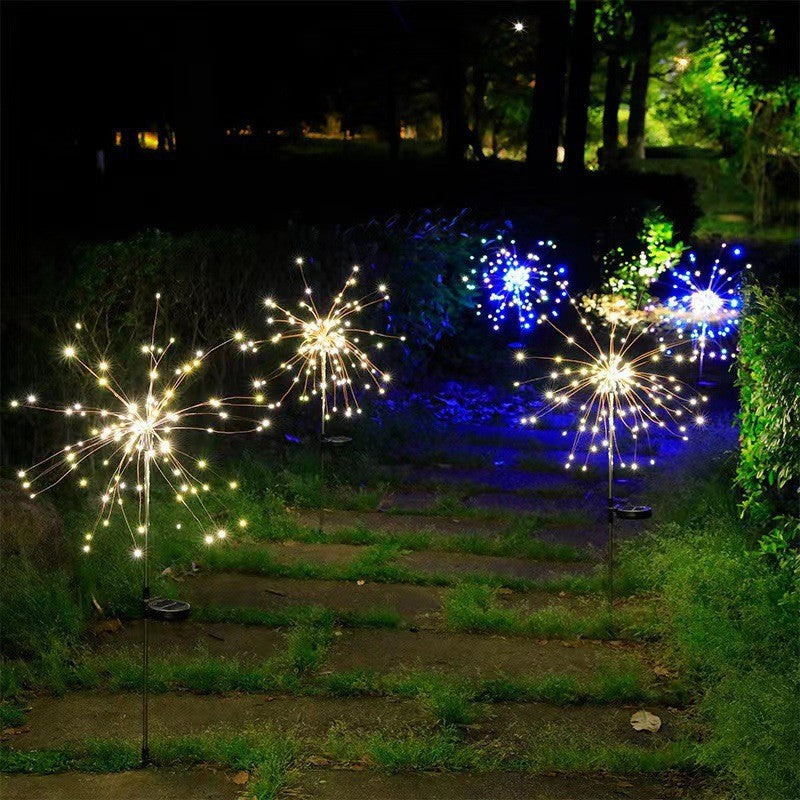 Two LED solar firework stake lights glowing white and blue starburst clusters