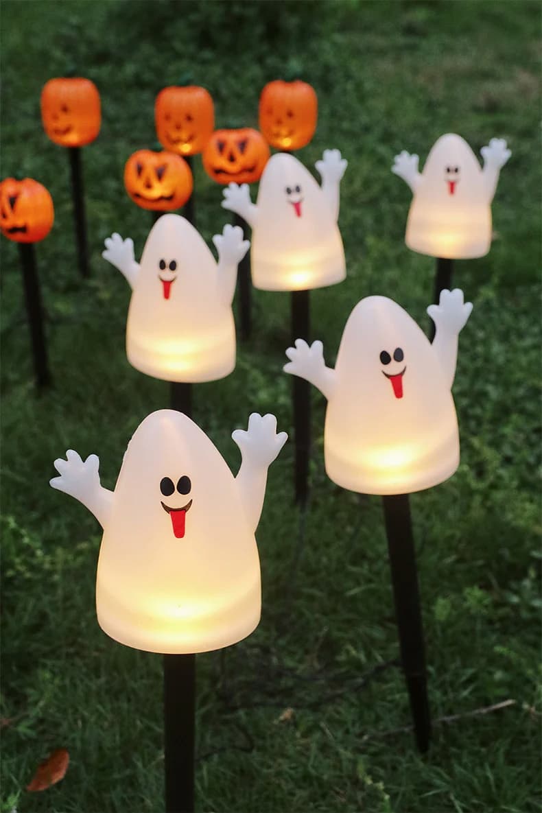 Glowing white ghost LED garden stake lights on black stakes with jack-o’-lanterns