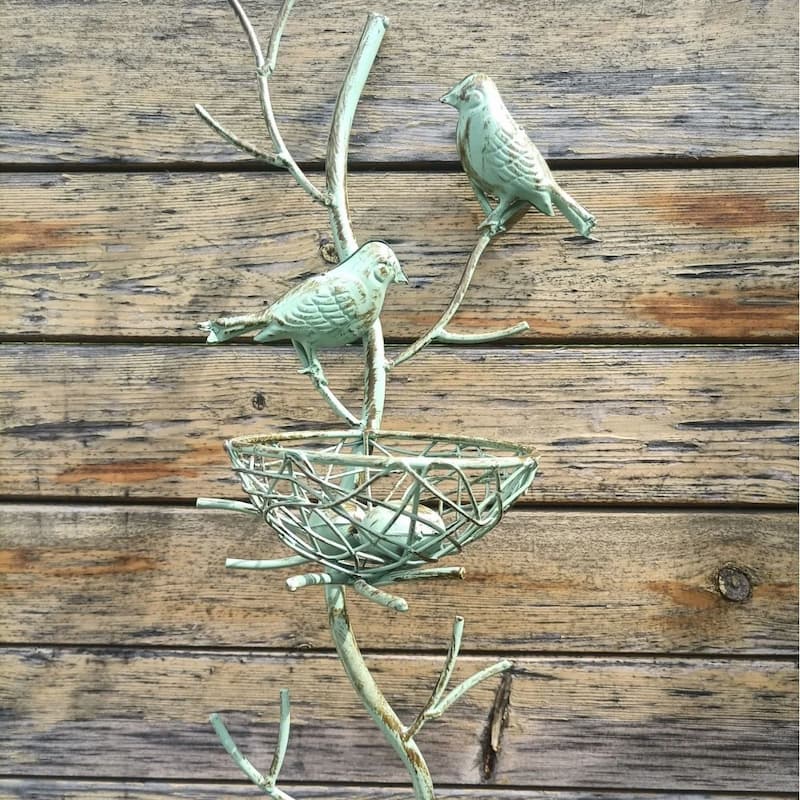 Green metal bird nest garden stake detail with two perched birds above round wire nest basket