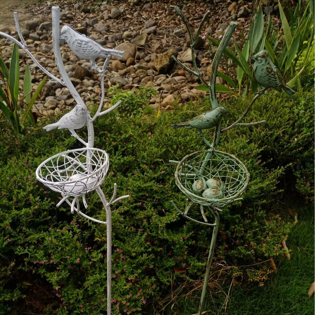 White metal garden stake trellis with two perched birds and round wire nest baskets