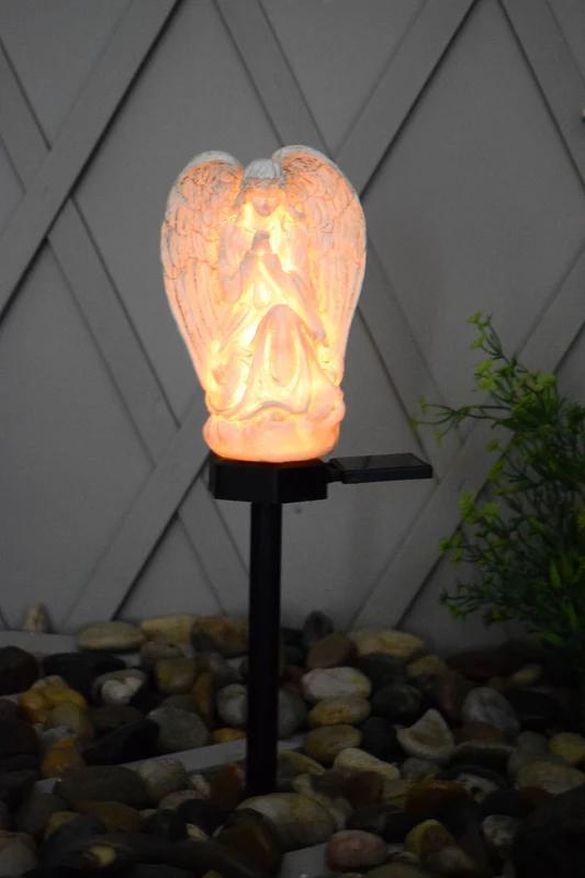 Glowing angel solar stake light with raised wings and lantern-style warm illumination