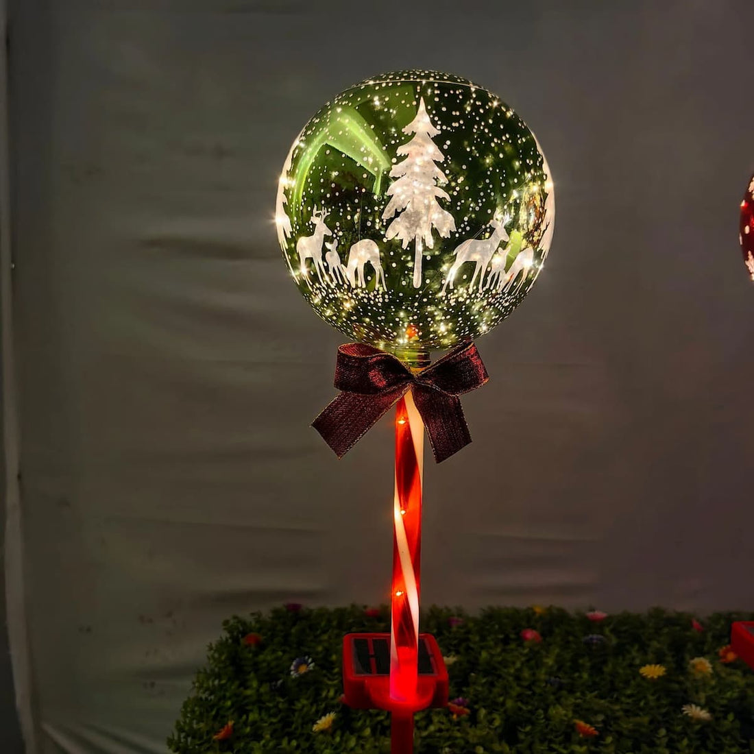 Grøn glitterkugleformet solcellelampe med varm hvid glød og mørkerød sløjfe