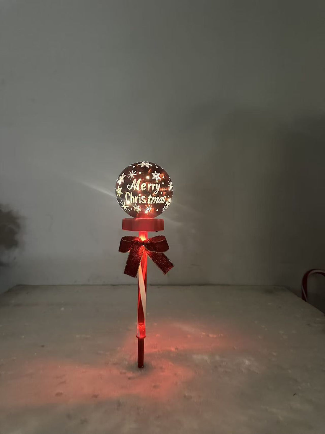 Solar Christmas ball lawn stake light with red ribbon bow, warm glowing globe