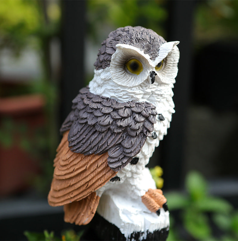 Close-up of a hand-painted owl solar garden stake light with detailed feathers