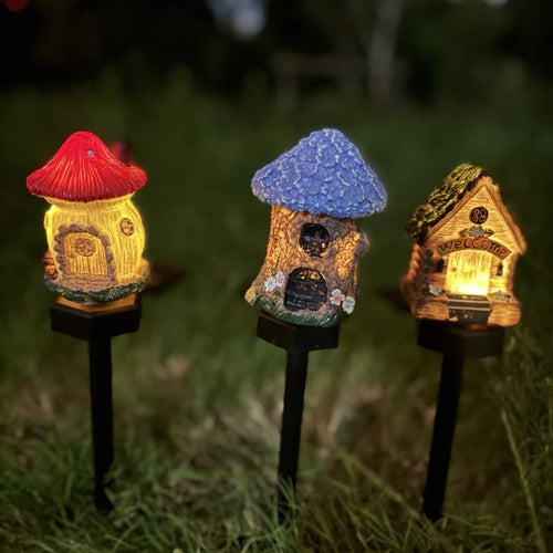 Solar fairy house garden stakes with red, blue, and golden roofs, glowing in grass