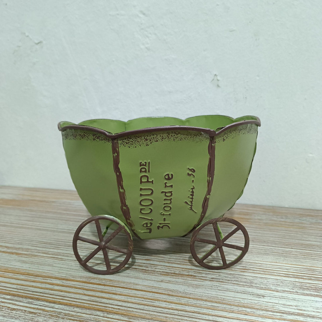 Green vintage metal cart planter with wheels and printed text