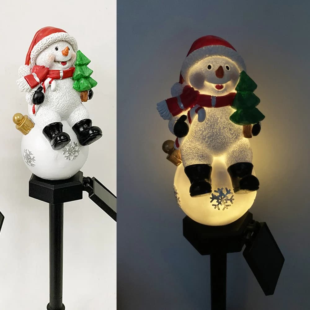 Solar snowman pathway stake light holding a green tree, warm glowing base on black stake