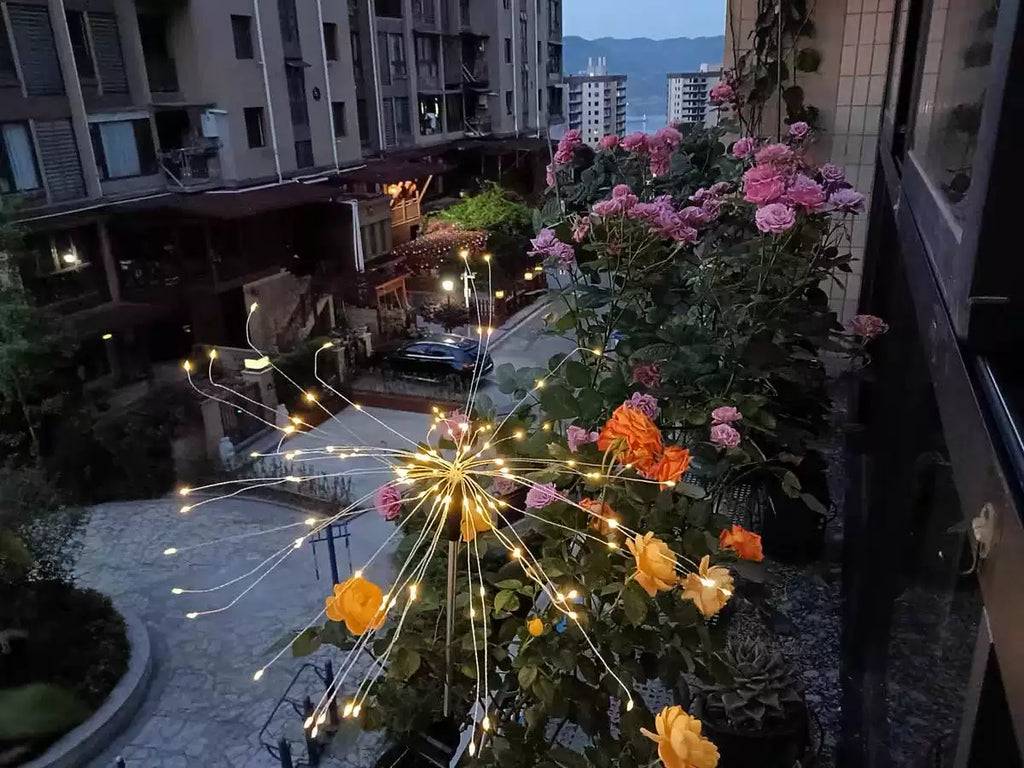 LED solar firework stake lights over flowers with warm gold starburst glow