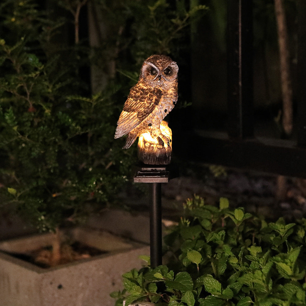 Single brown owl solar garden stake light with warm glow under night garden lighting