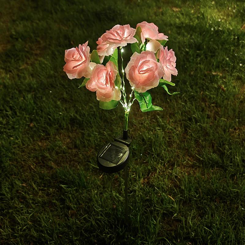 Solar rose garden stake light with pink fabric roses, green leaves, and glowing solar base