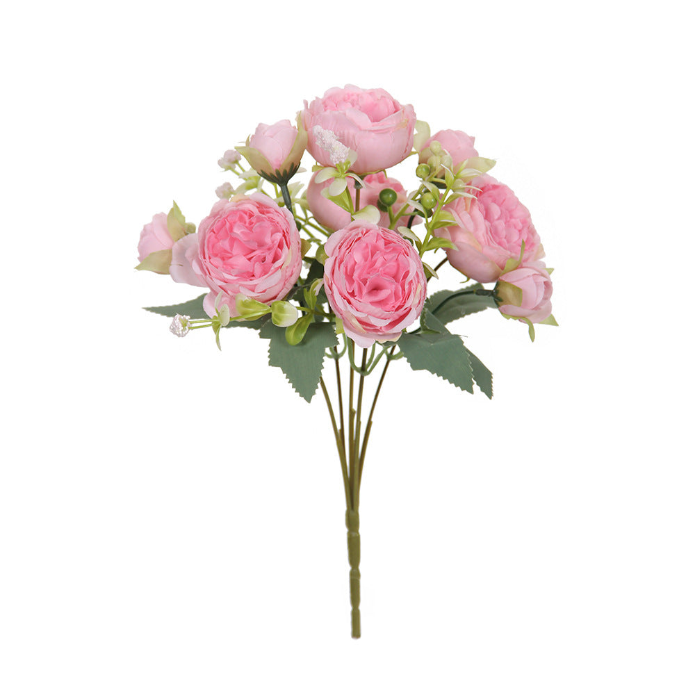 Pink faux peony flower bunch with green leaves on a single stem, unvased.
