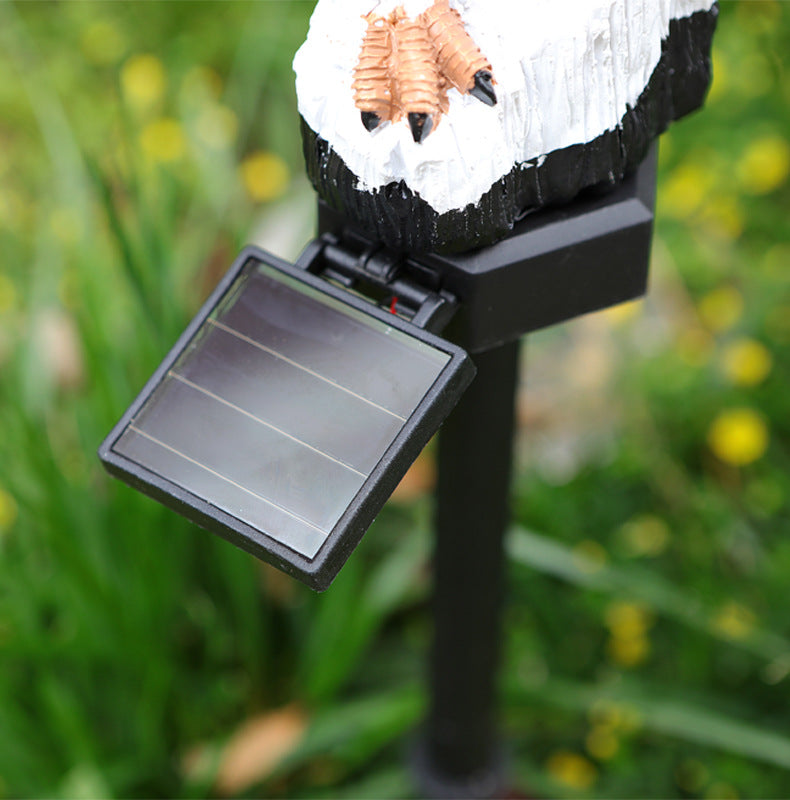 Solar garden stake light with frosted panel and black base beneath owl figurine