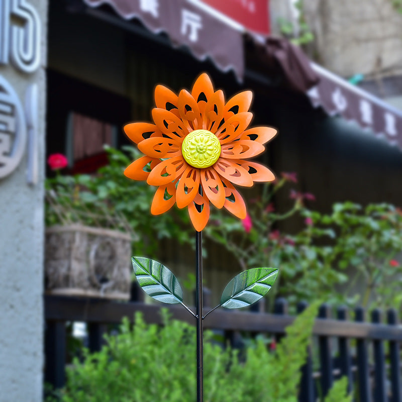 Orange metal wind spinner flower garden stake with green leaves