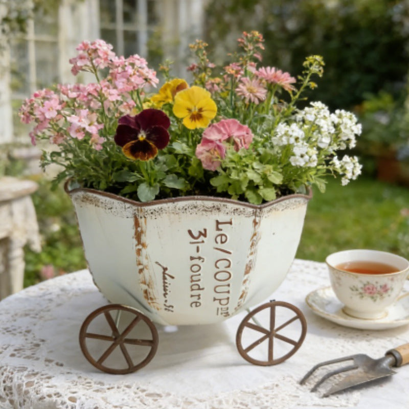 Vintage metal cart planter with vintage ivory finish and blooming flowers on wheels