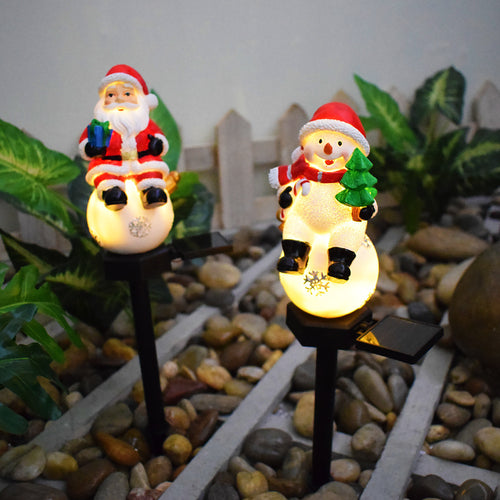 Solar Christmas Santa and snowman light-up pathway stakes with glowing faces.