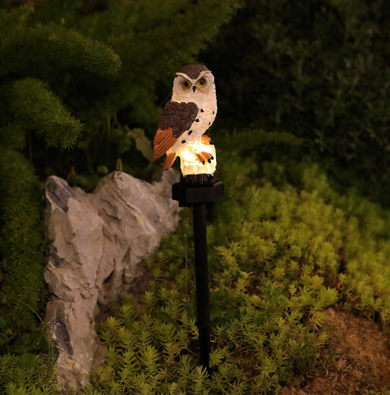 Single cream-brown owl solar garden stake light with warm glow beside rocks