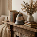 Decorative items on a wooden surface including books, a bell, and a vase with dried plants.