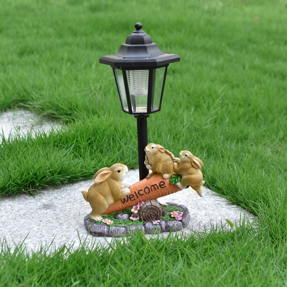 Solar LED rabbit garden statue with black lantern and three tan rabbits by welcome sign