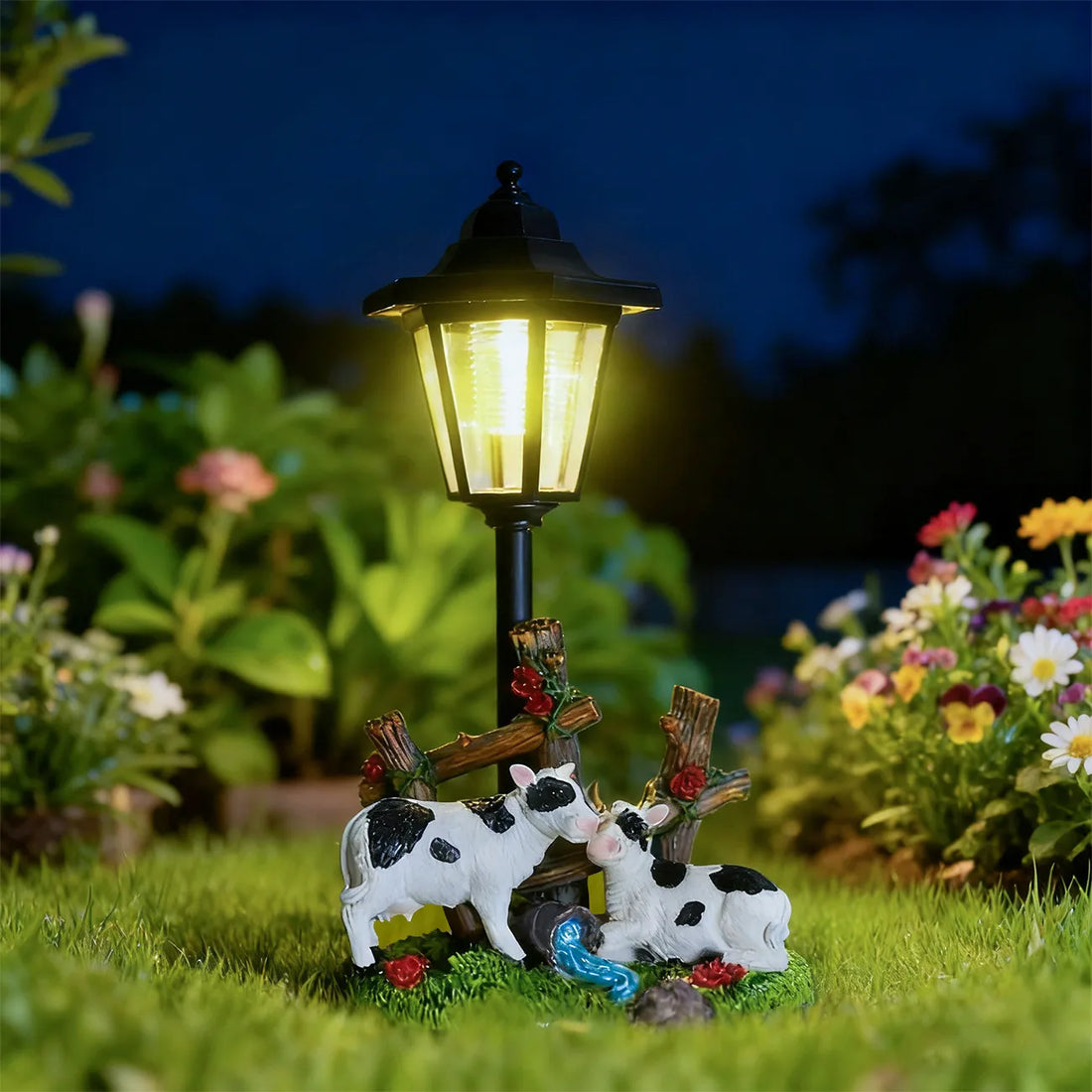 Solar LED garden statue with glowing lantern and two black-and-white cow figures
