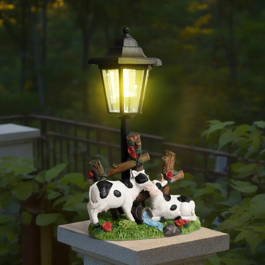 Solar LED garden statue with glowing lantern and three black-and-white cow figures