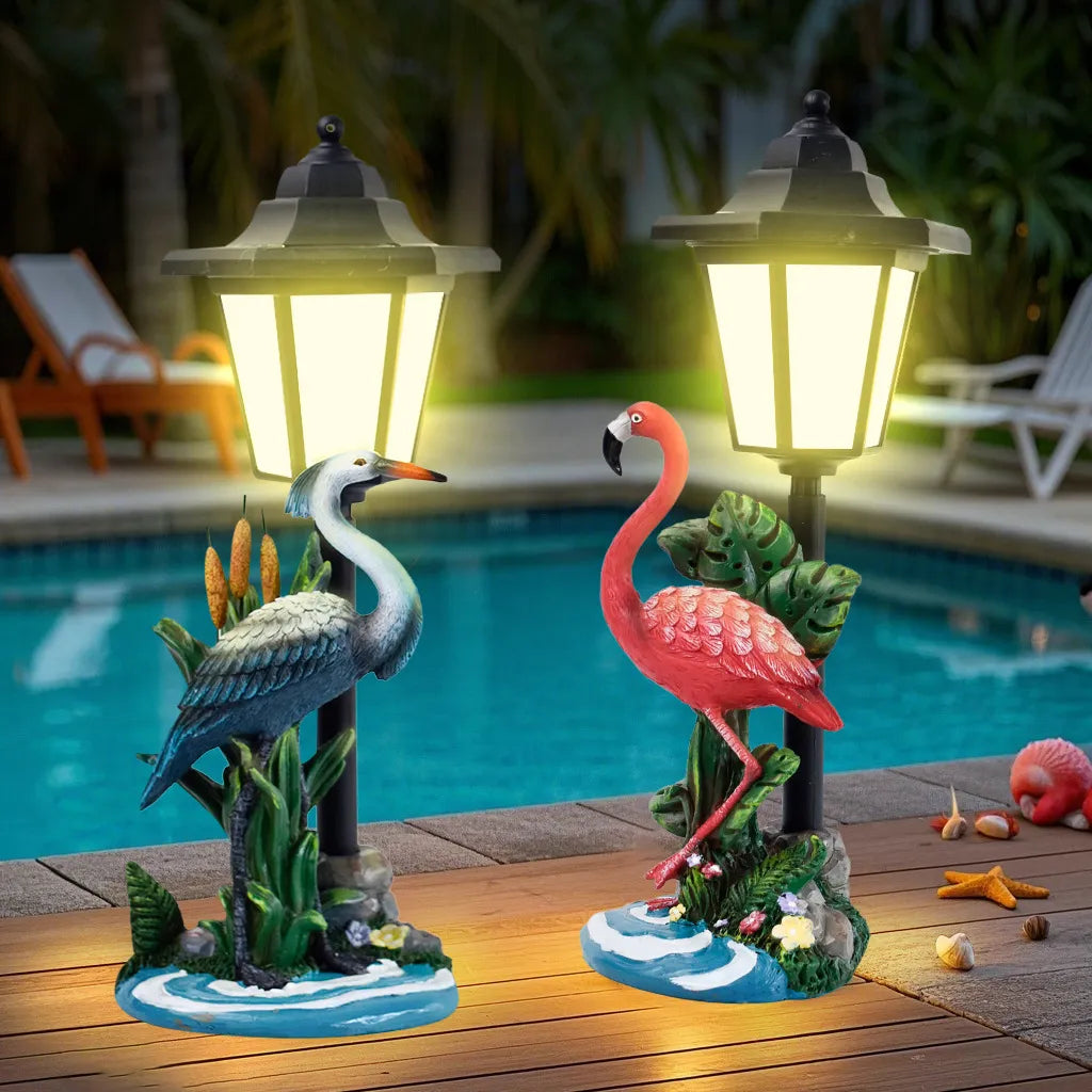 Flamingo and heron garden resin statues with glowing LED lanterns by pool